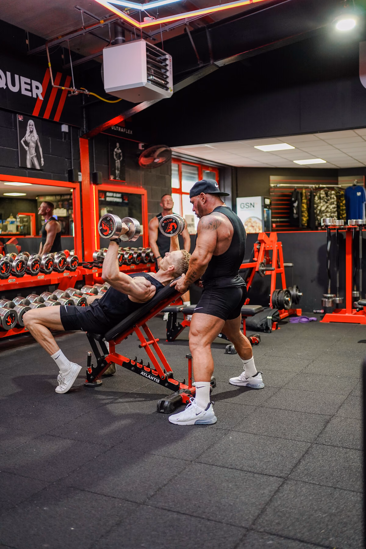 A coach guiding a client’s arm through a lat pulldown